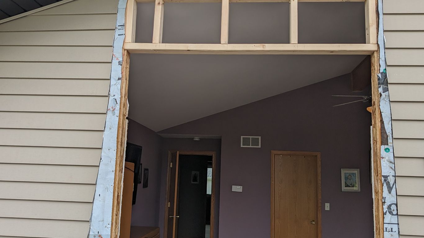 Exterior wall under construction with new window framing and siding.
