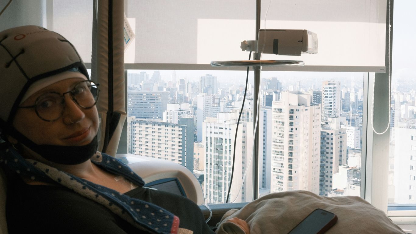 Woman in medical cap sits by window overlooking city.