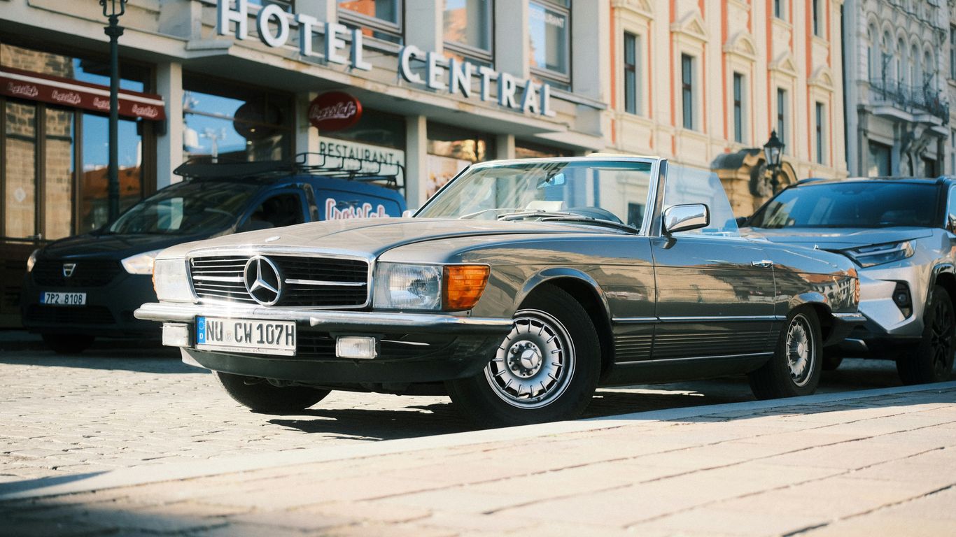 A vintage mercedes sits in front of a hotel.