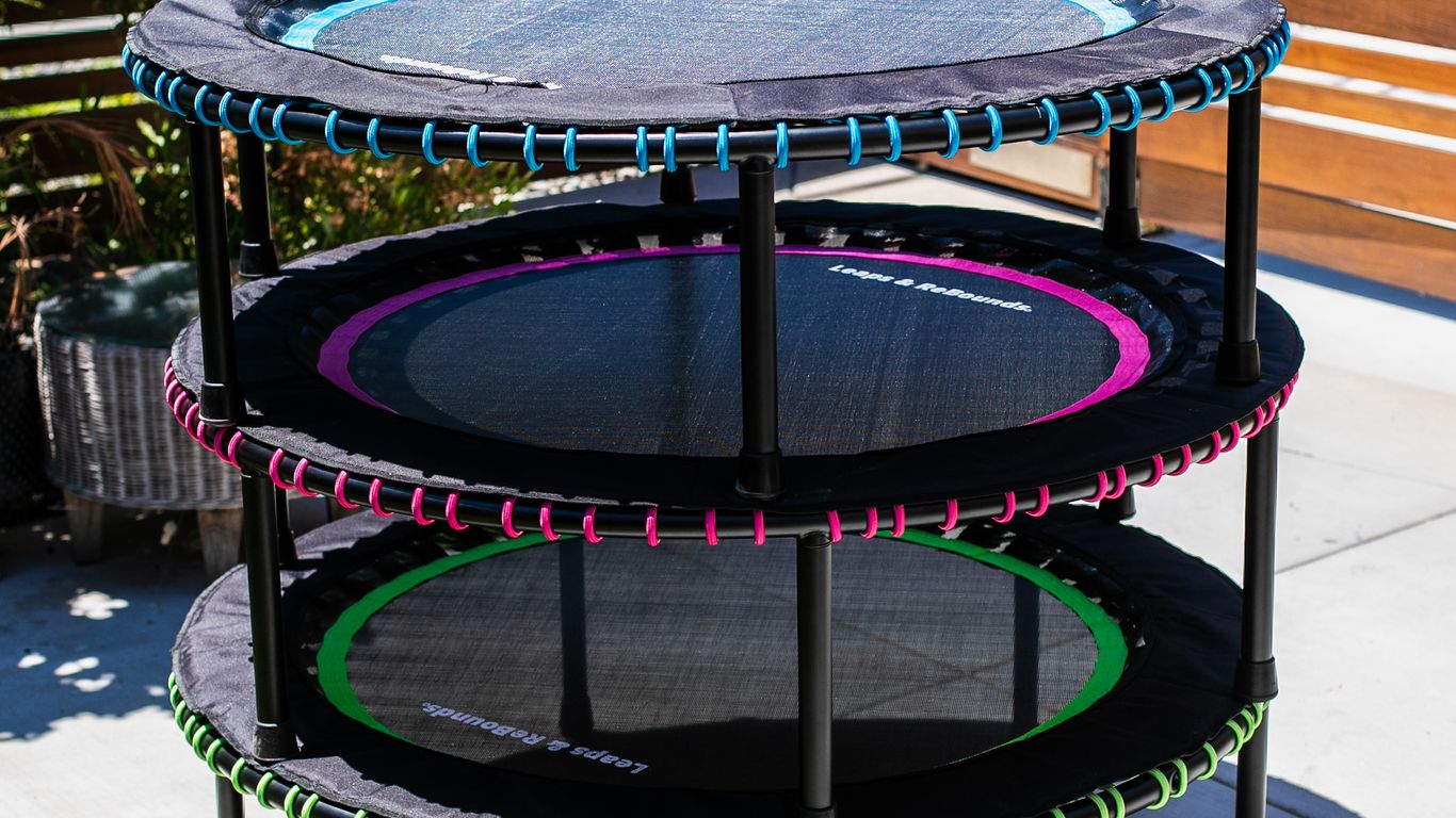 Three mini trampolines stacked outdoors on a sunny patio.