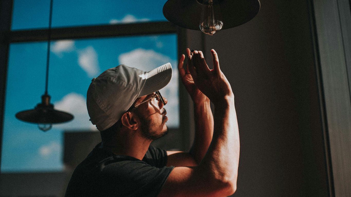 man in black shirt wearing white cap holding clear glass lamp
