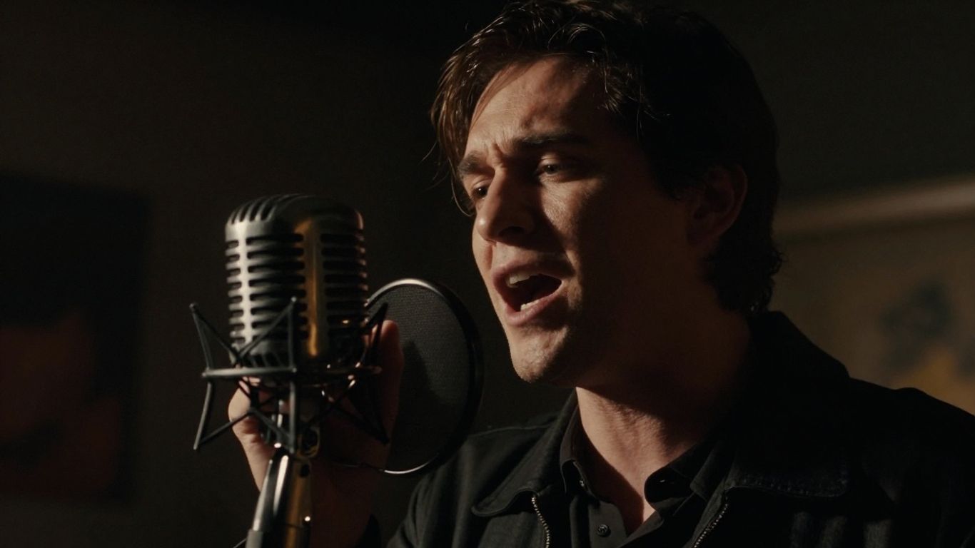 Singer performing with a large microphone in a studio.