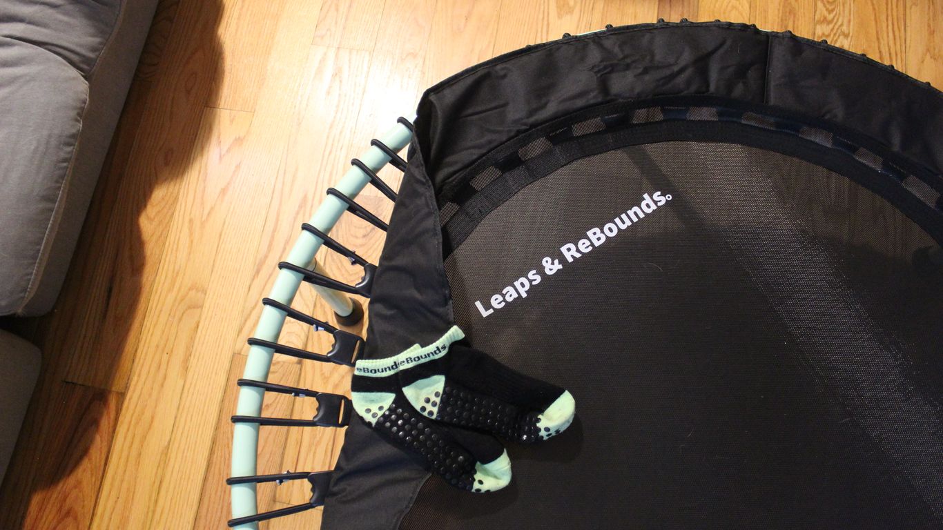 Mini trampoline with grip socks on it, wooden floor background.