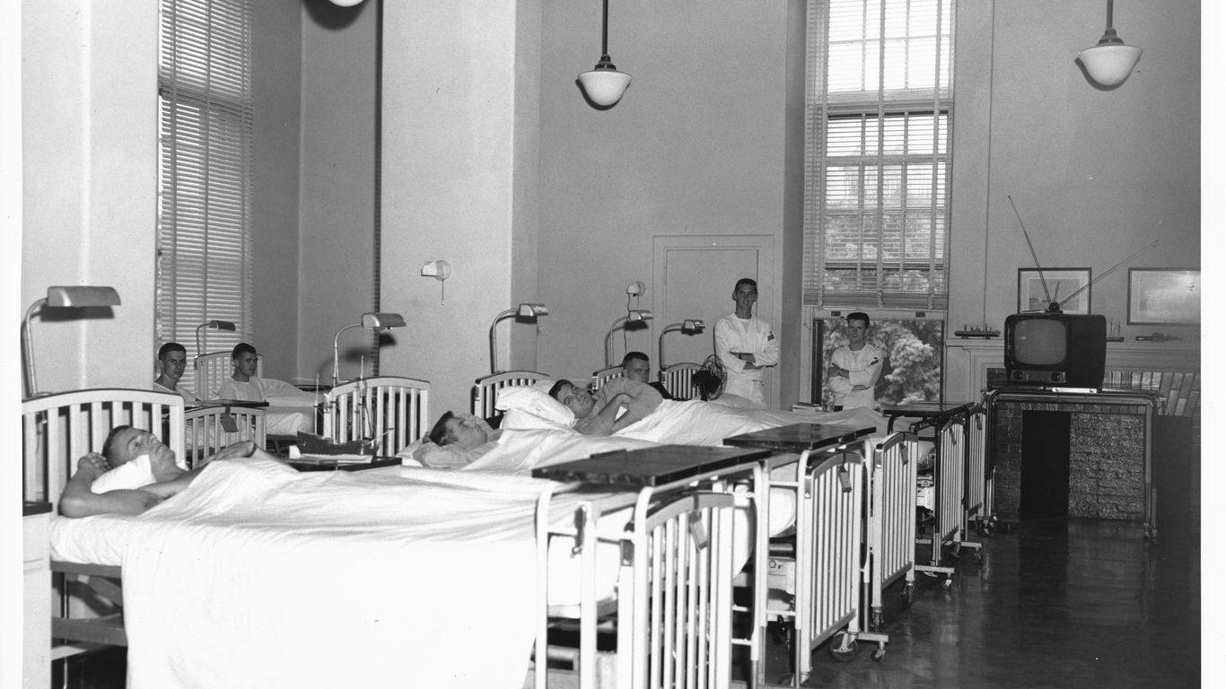 Patients in hospital beds with nurses nearby