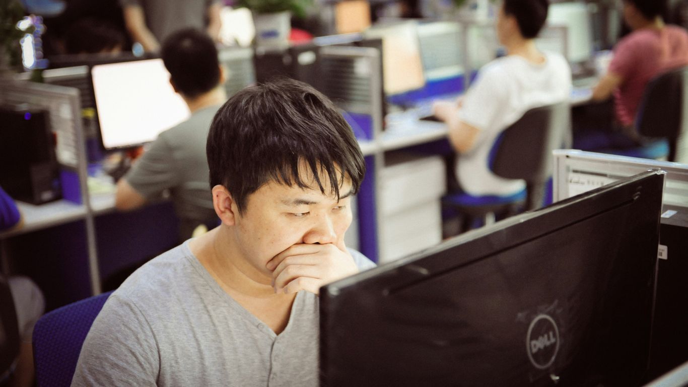 Man yawning while working at computer in office