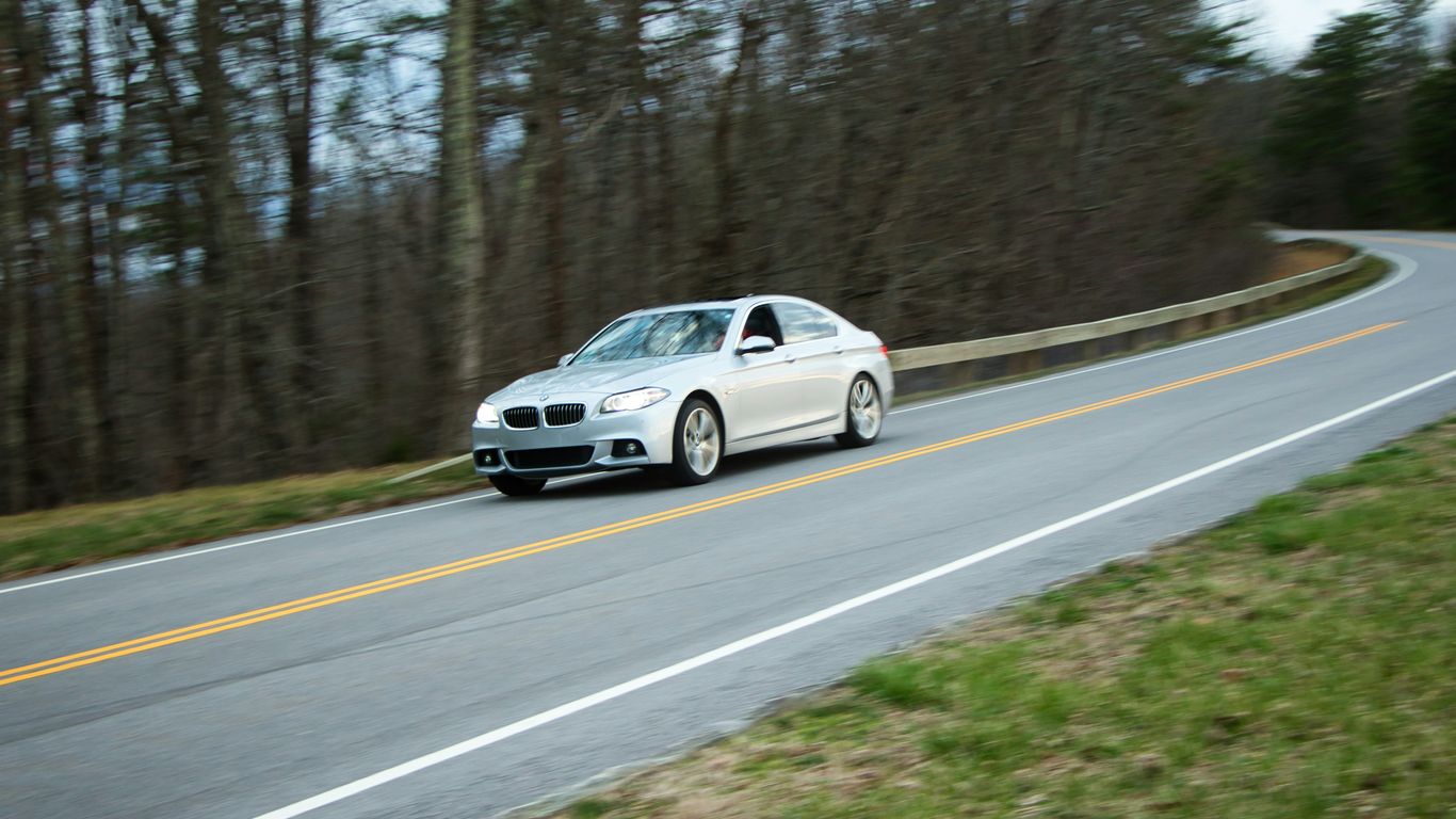 A silver car driving on a winding road.