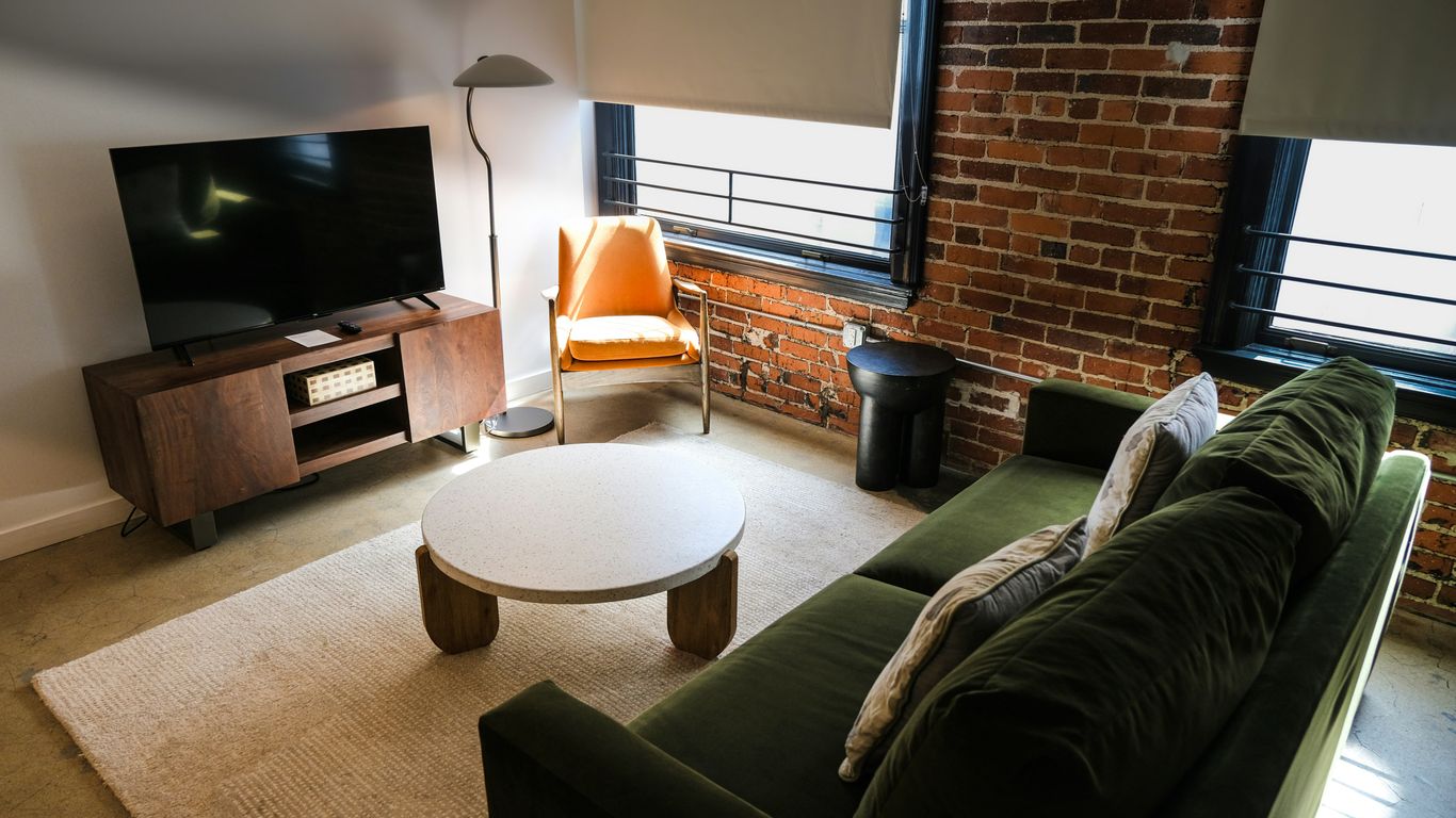 Modern living room with green sofa and brick wall.
