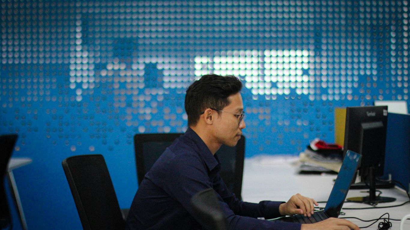 a man sitting at a desk using a laptop computer