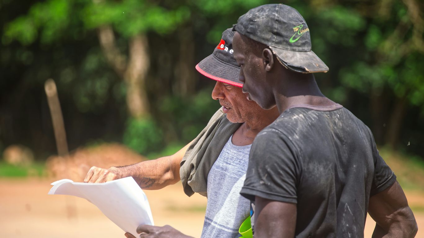 Two men looking at a document outdoors
