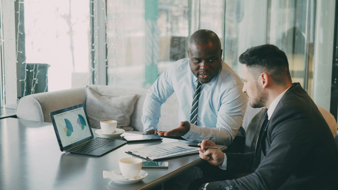 Two businessmen discussing charts on a laptop.