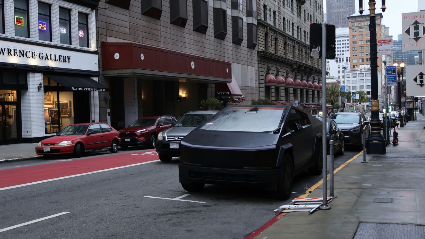 A black tesla cybertruck parked on a city street.