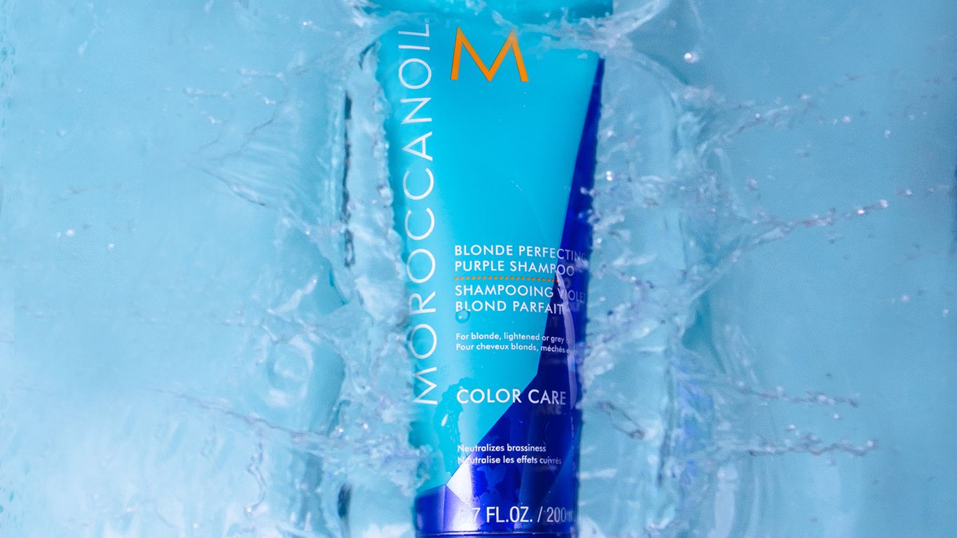 Moroccanoil shampoo submerged in water creating dynamic splash effects.