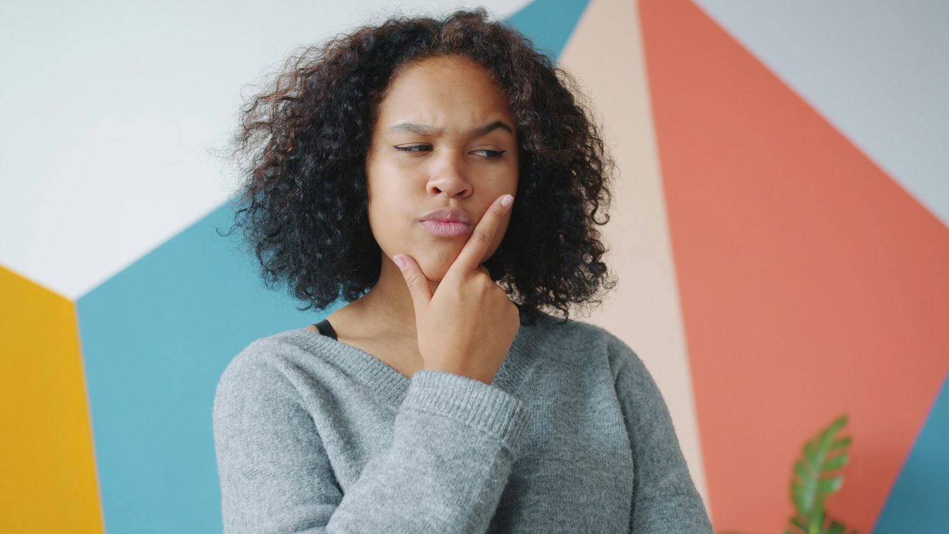 Young woman with hand on chin, thinking.
