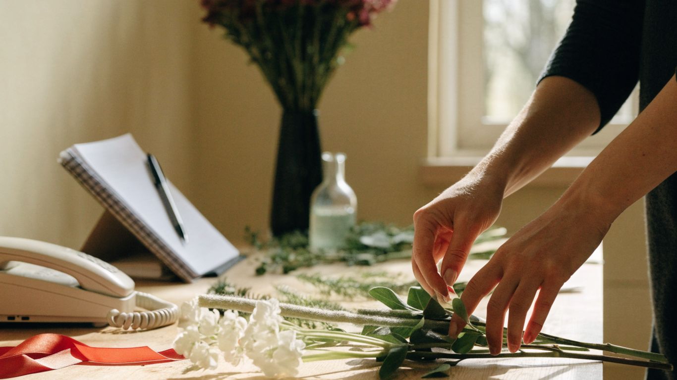 Florist arranging flowers beside a phone and notepad