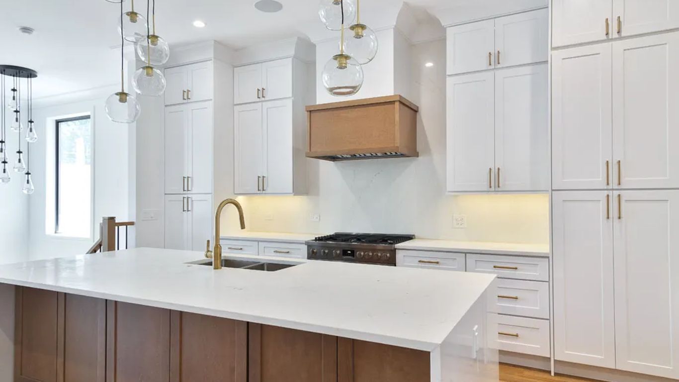 Modern kitchen with white cabinets, island, and brass accents.