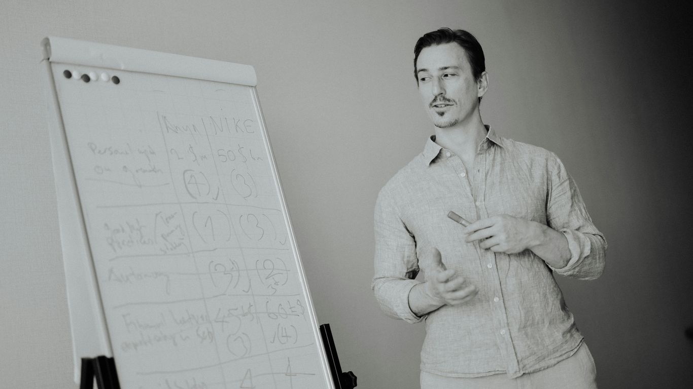 Man standing next to a whiteboard with notes.