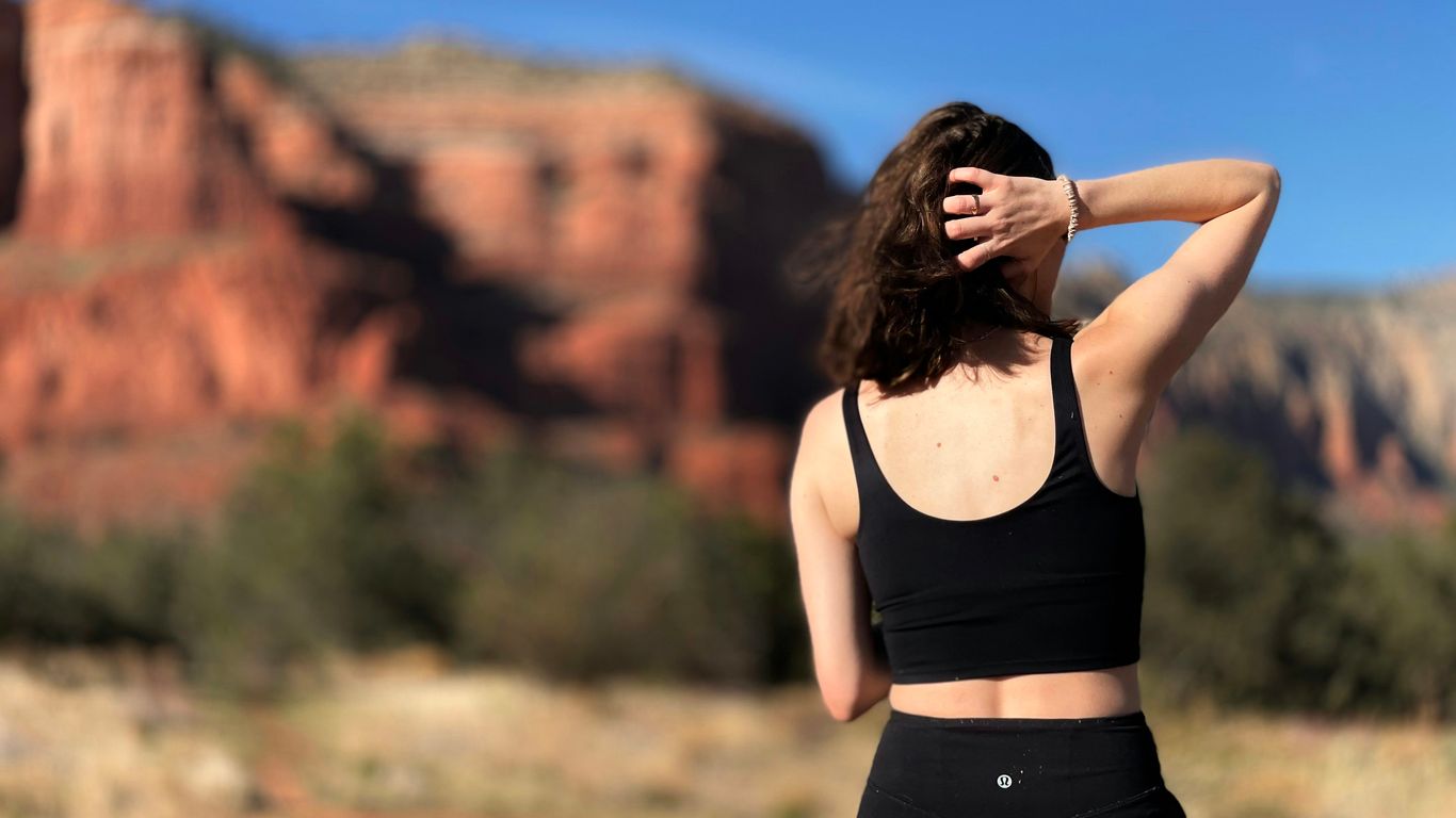 a woman in a black sports bra top and leggings stands in front of