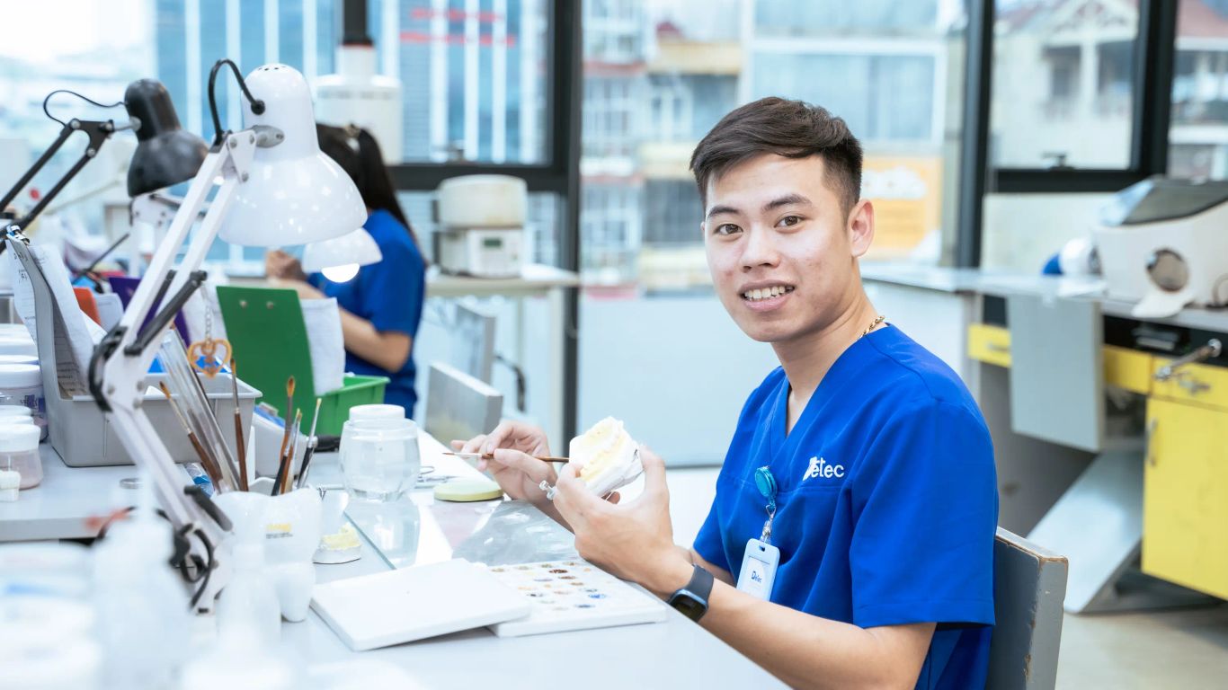 A person works on a dental prosthesis in a lab setting.