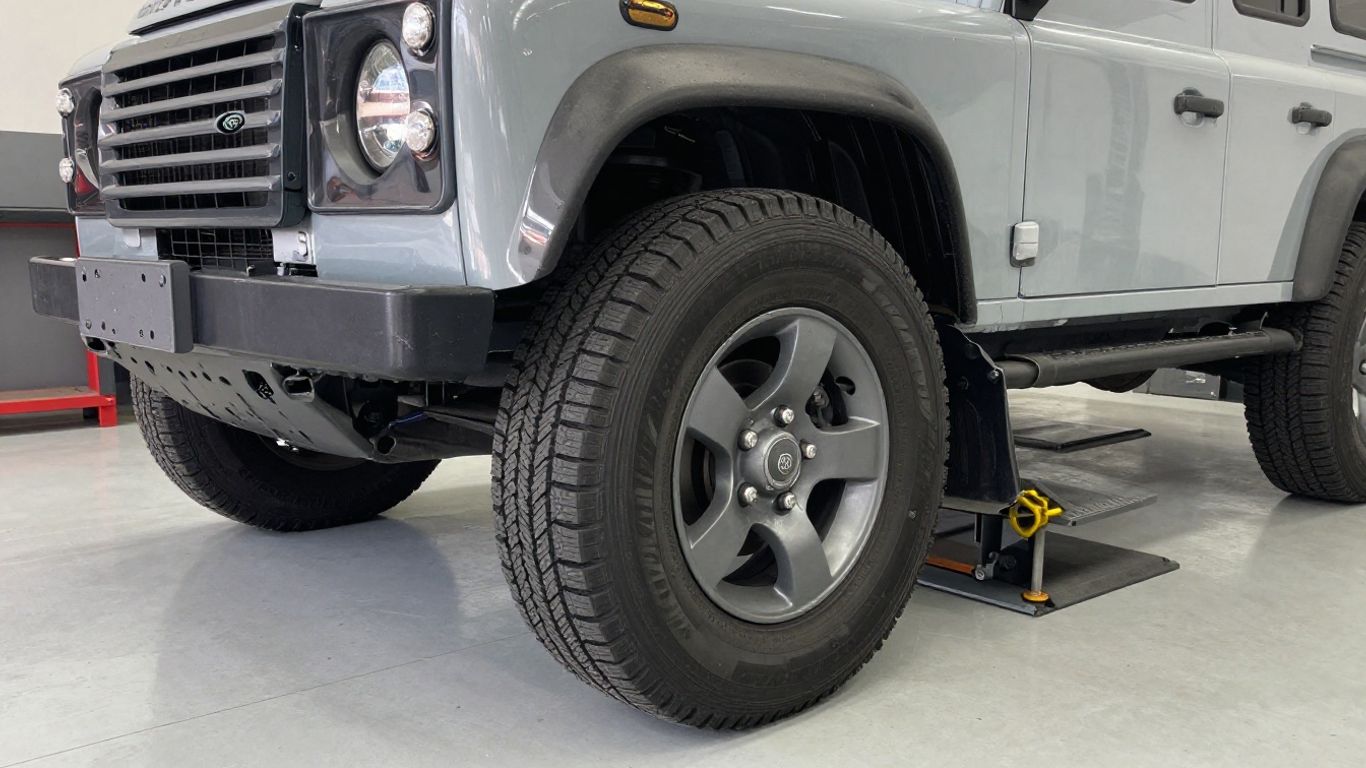 Unevenly worn Land Rover tires beside alignment equipment