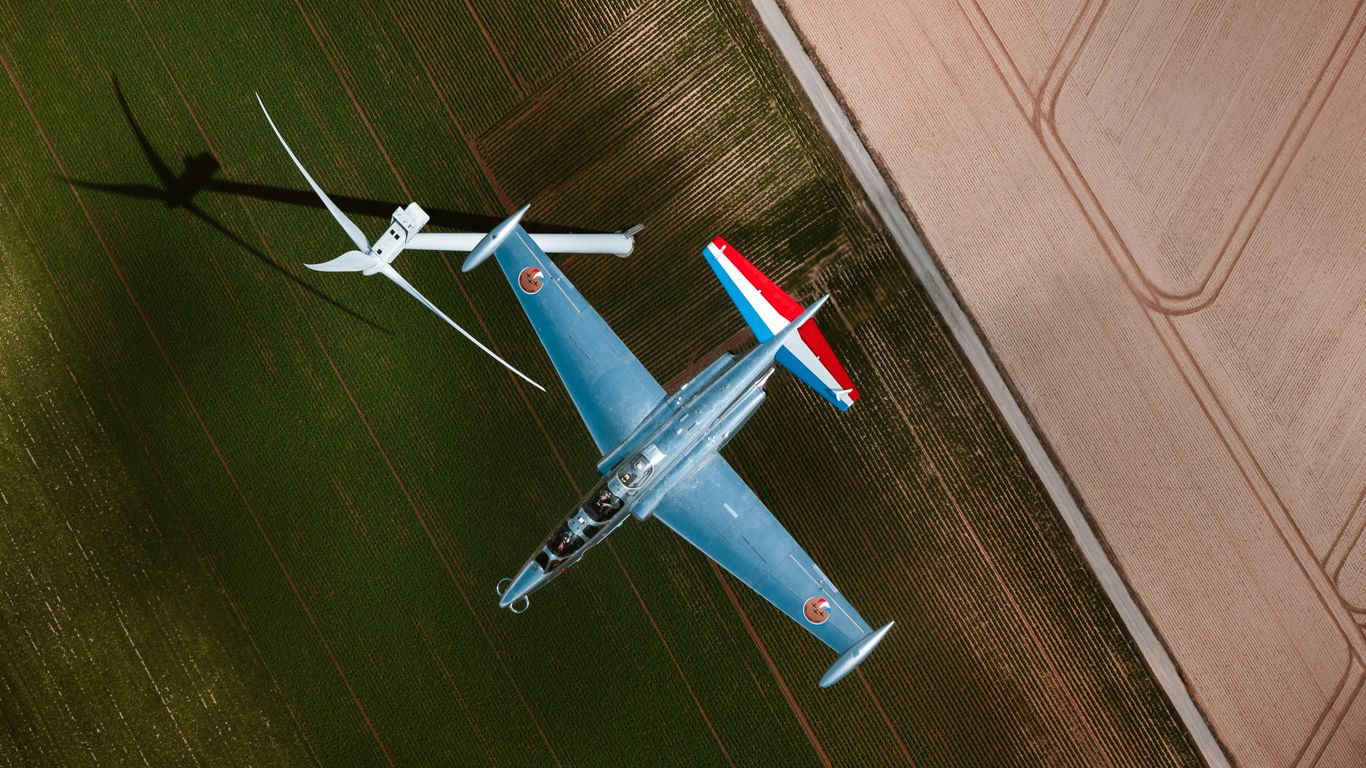 A series of small drones flying in formation above a landscape