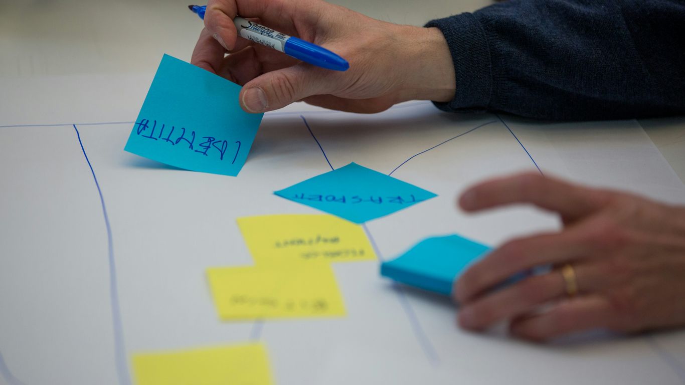 person holding blue pen writing on white paper