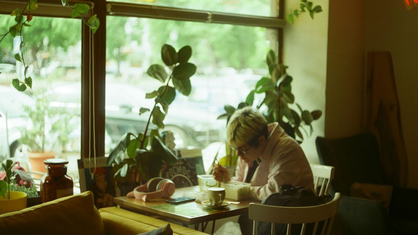 A woman sitting at a table in front of a window
