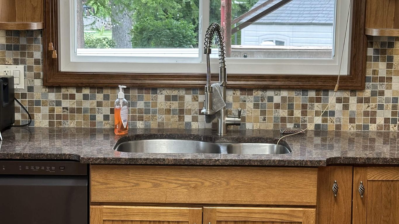 Kitchen sink with a window view of trees and scaffolding.
