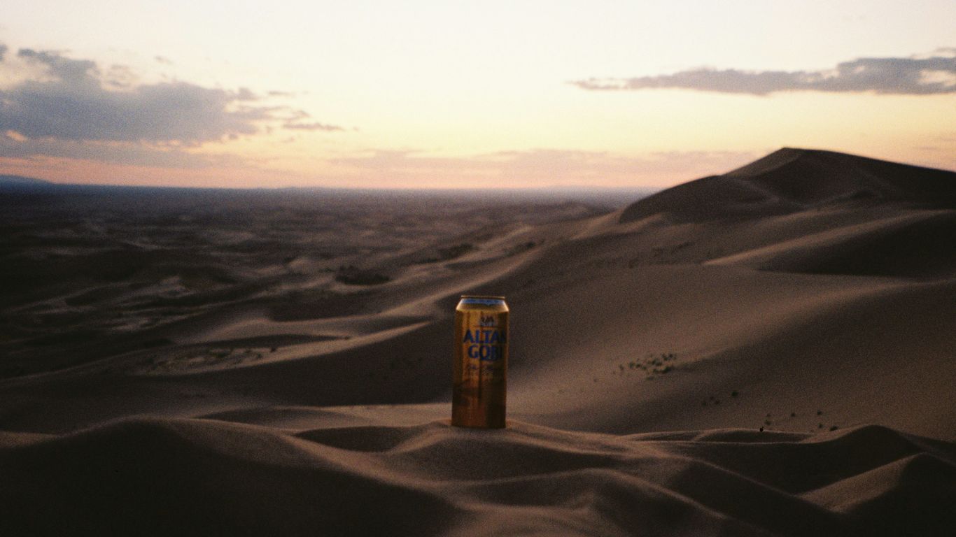Desert dunes at sunset with a tall structure.