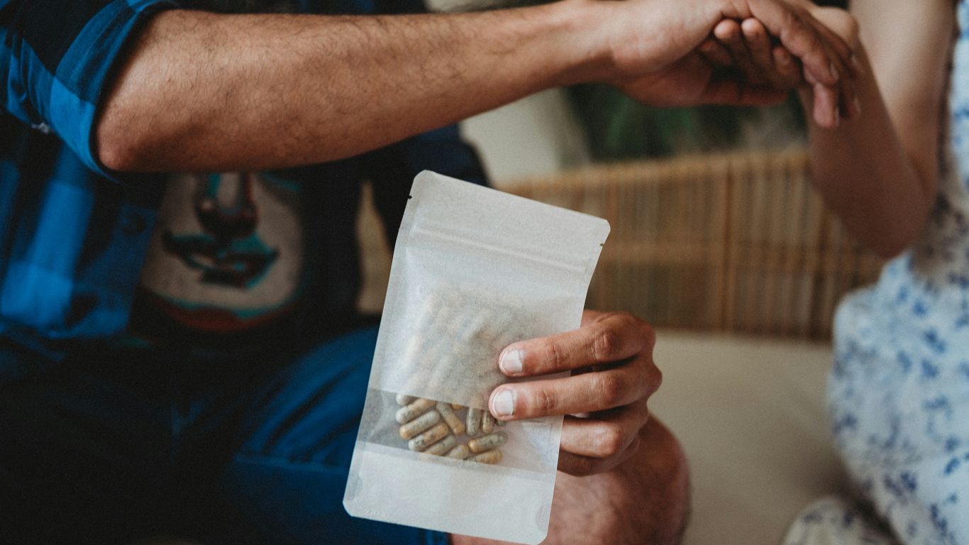 a man and a woman holding a bag of pills