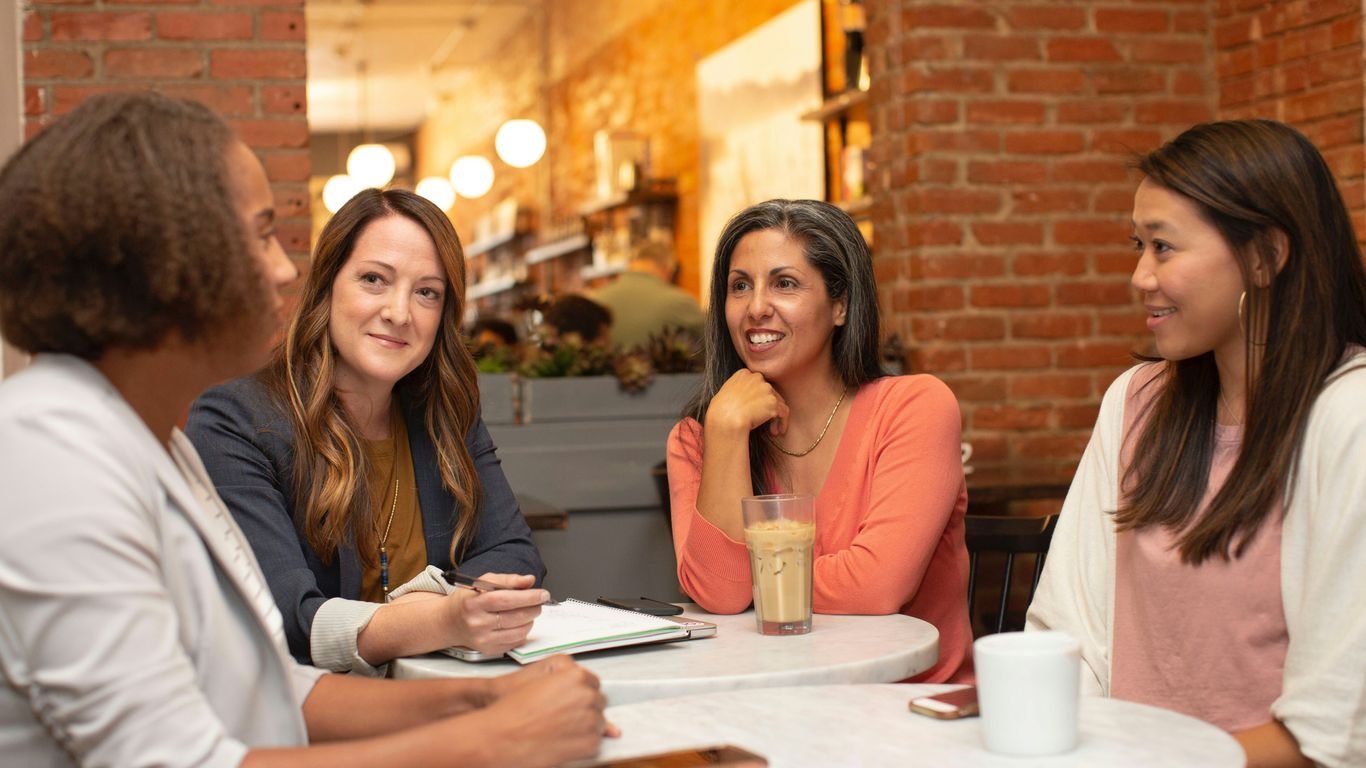 four women chatting at cafe table