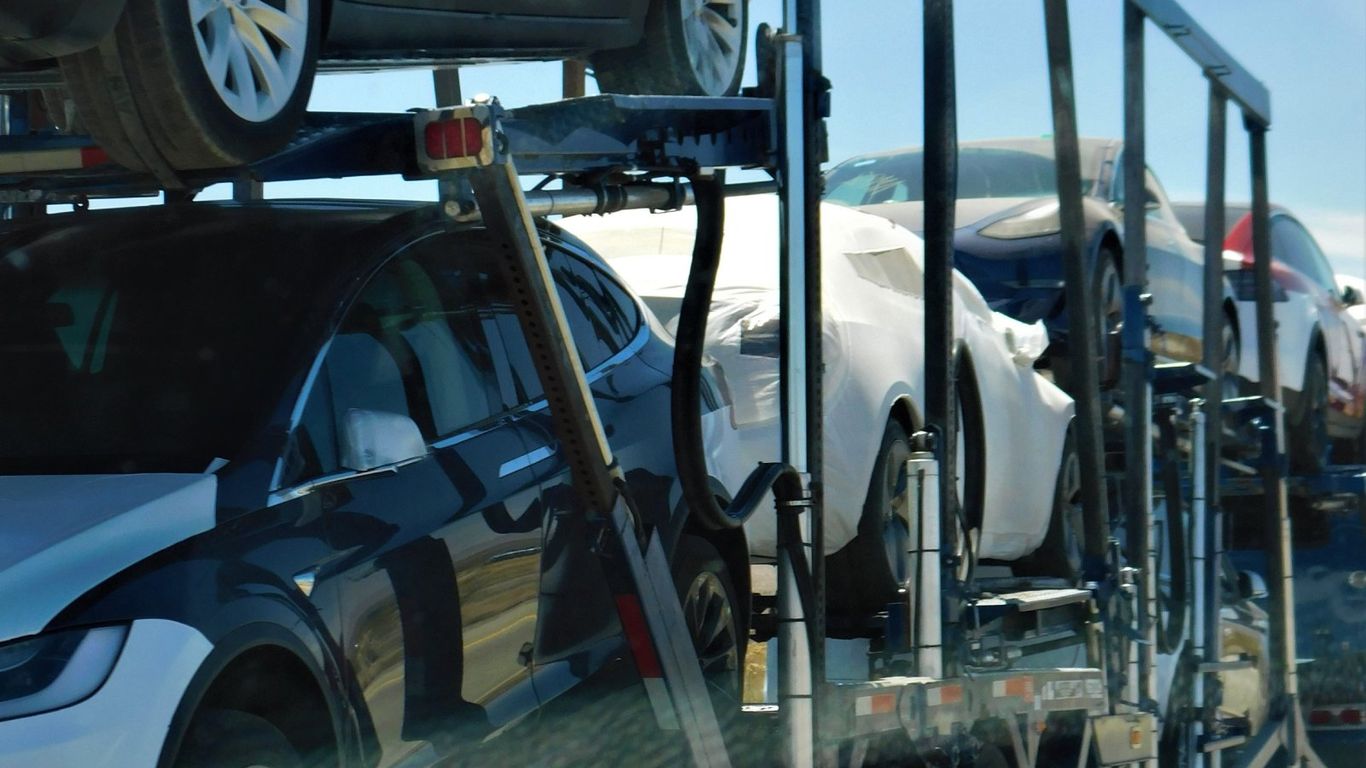 A car carrier truck transporting multiple vehicles on a sunny day.