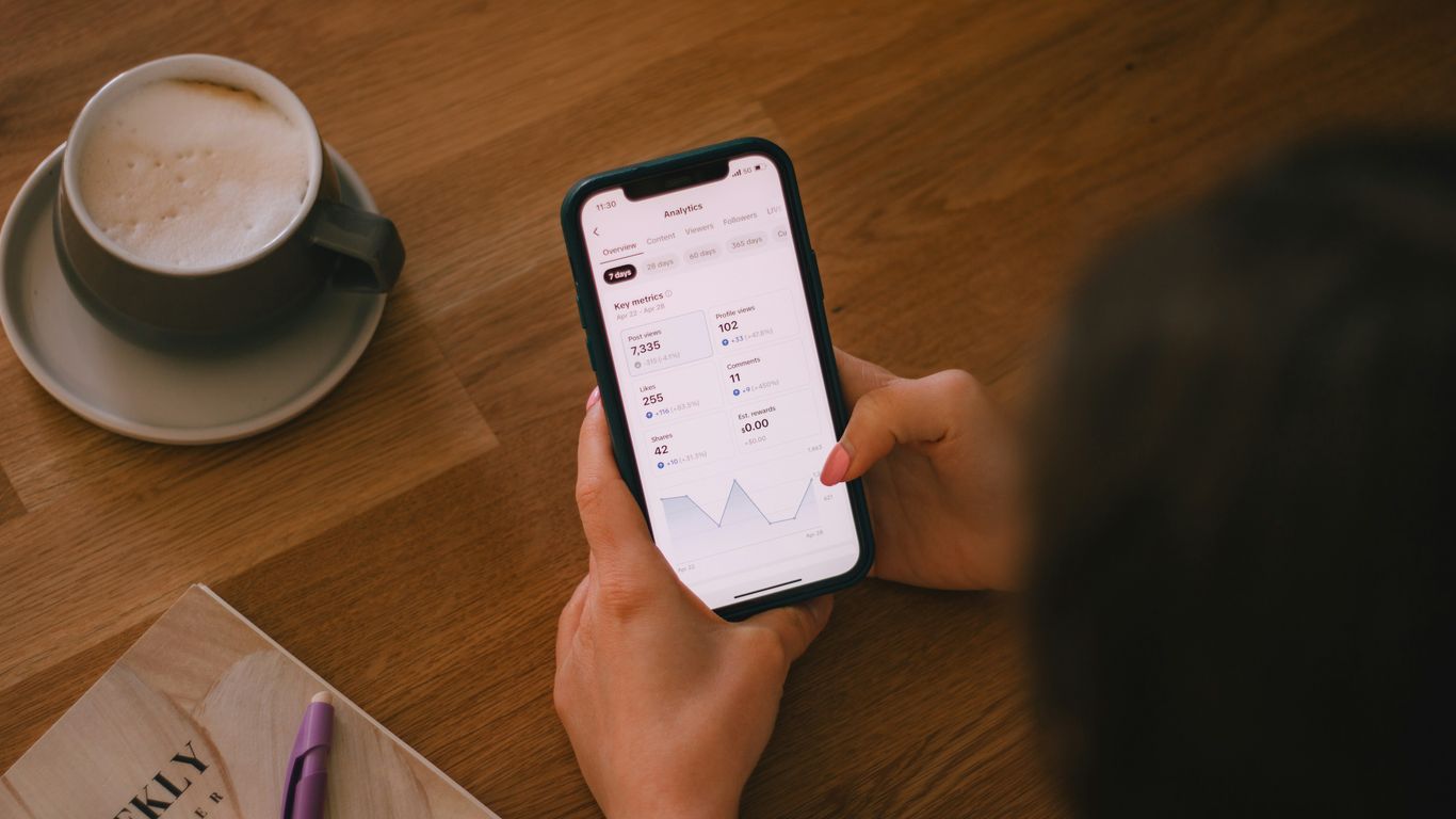 Checking finances on a phone with coffee.