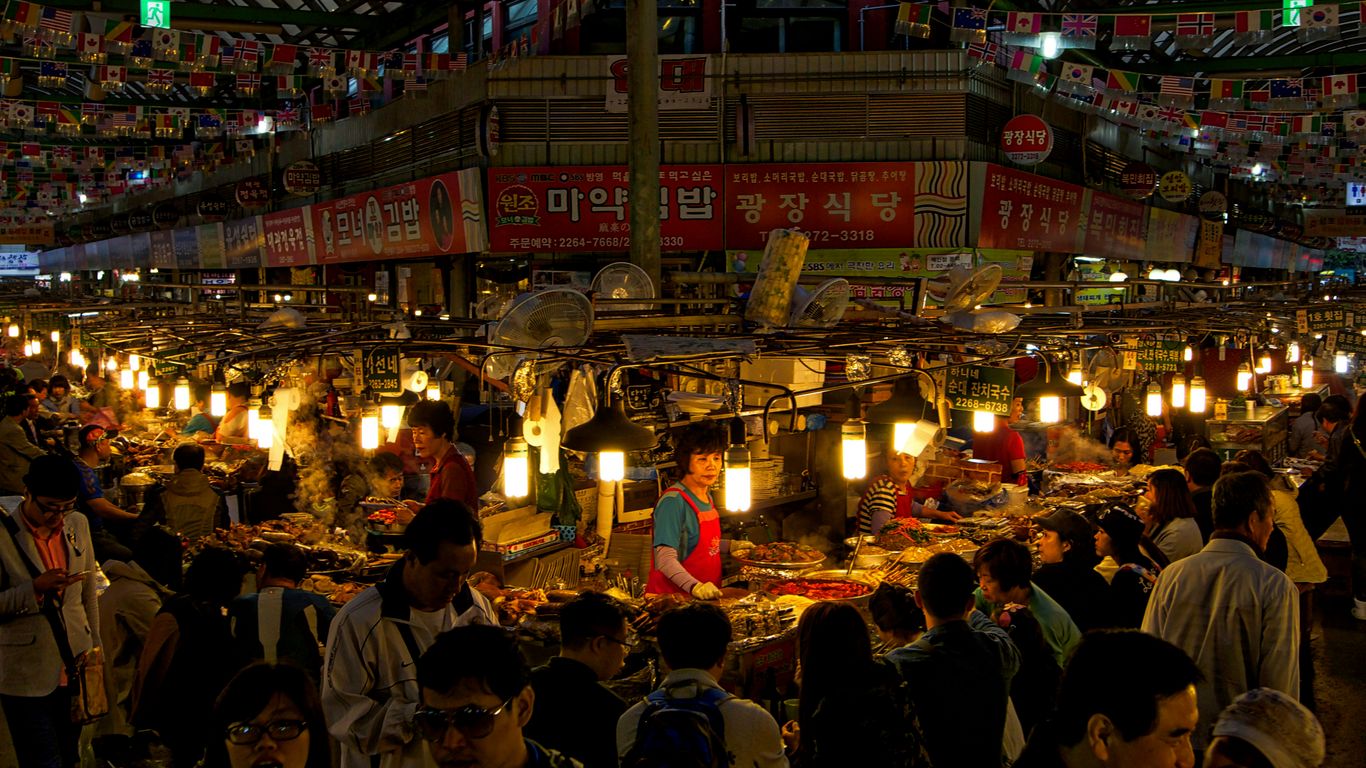 Travelers walking past stalls in a food market