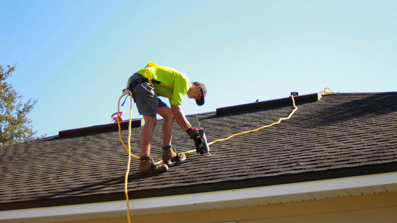 a man working on a roof with a power drill