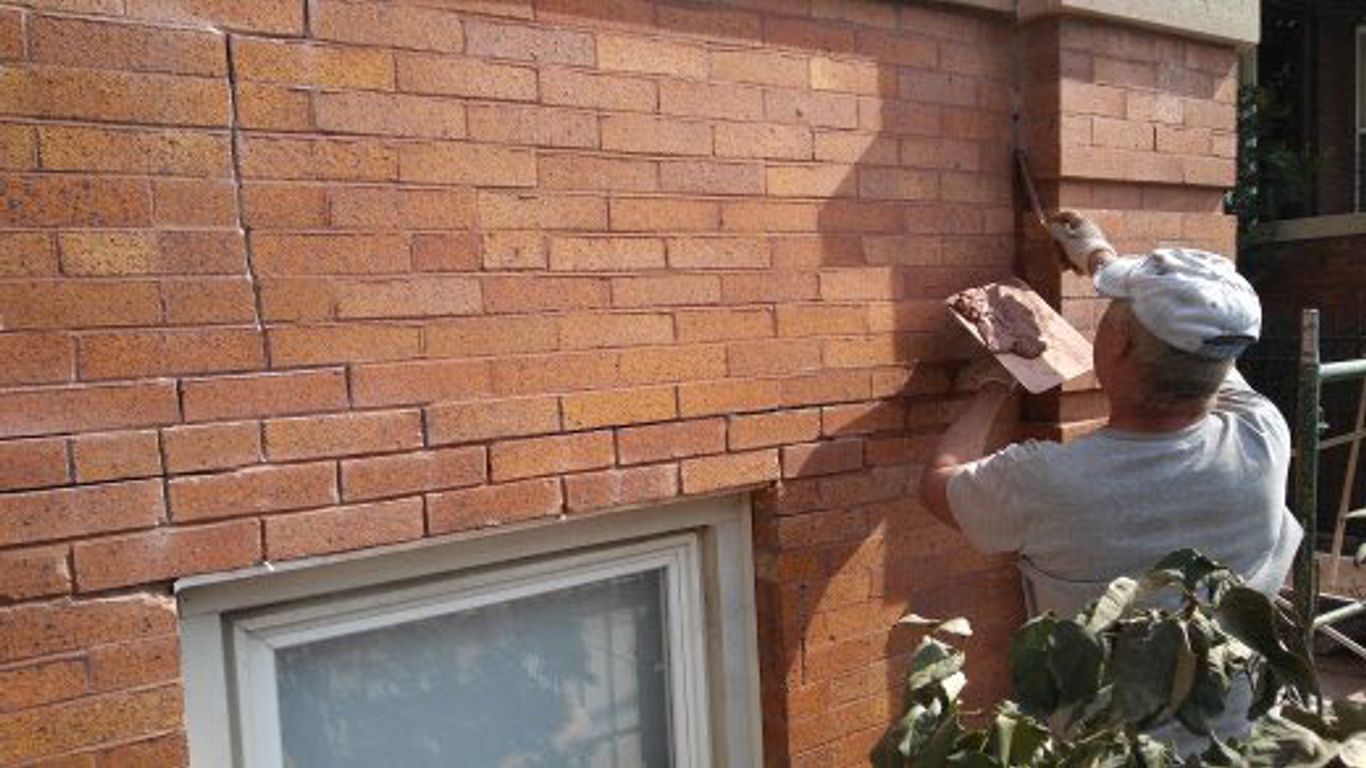 A person is repairing a brick wall with mortar.