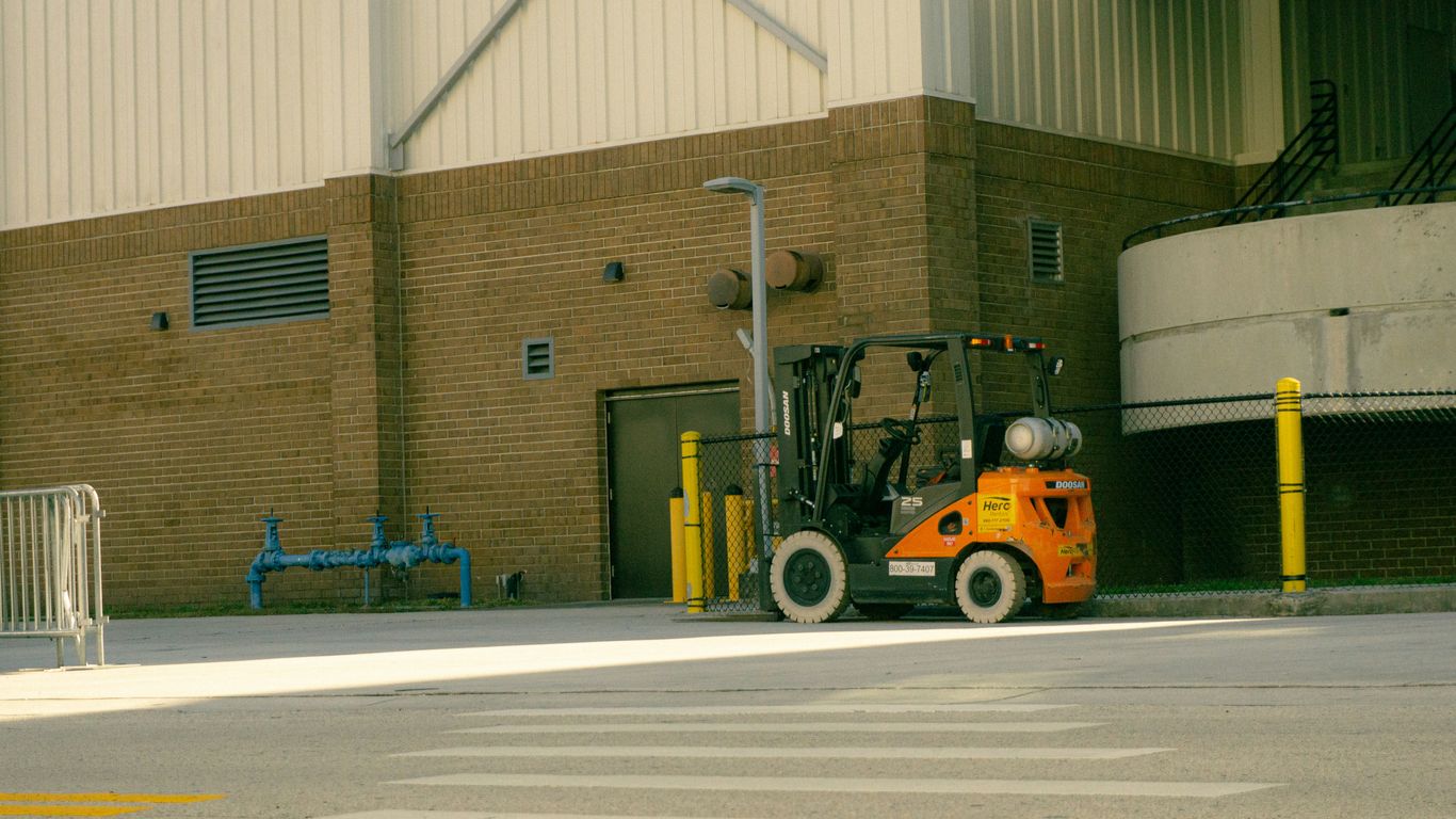 Orange forklift parked outside industrial building
