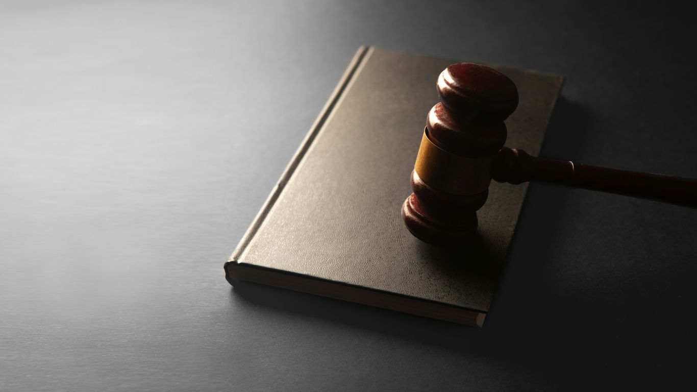 A wooden gavel rests on a closed book.