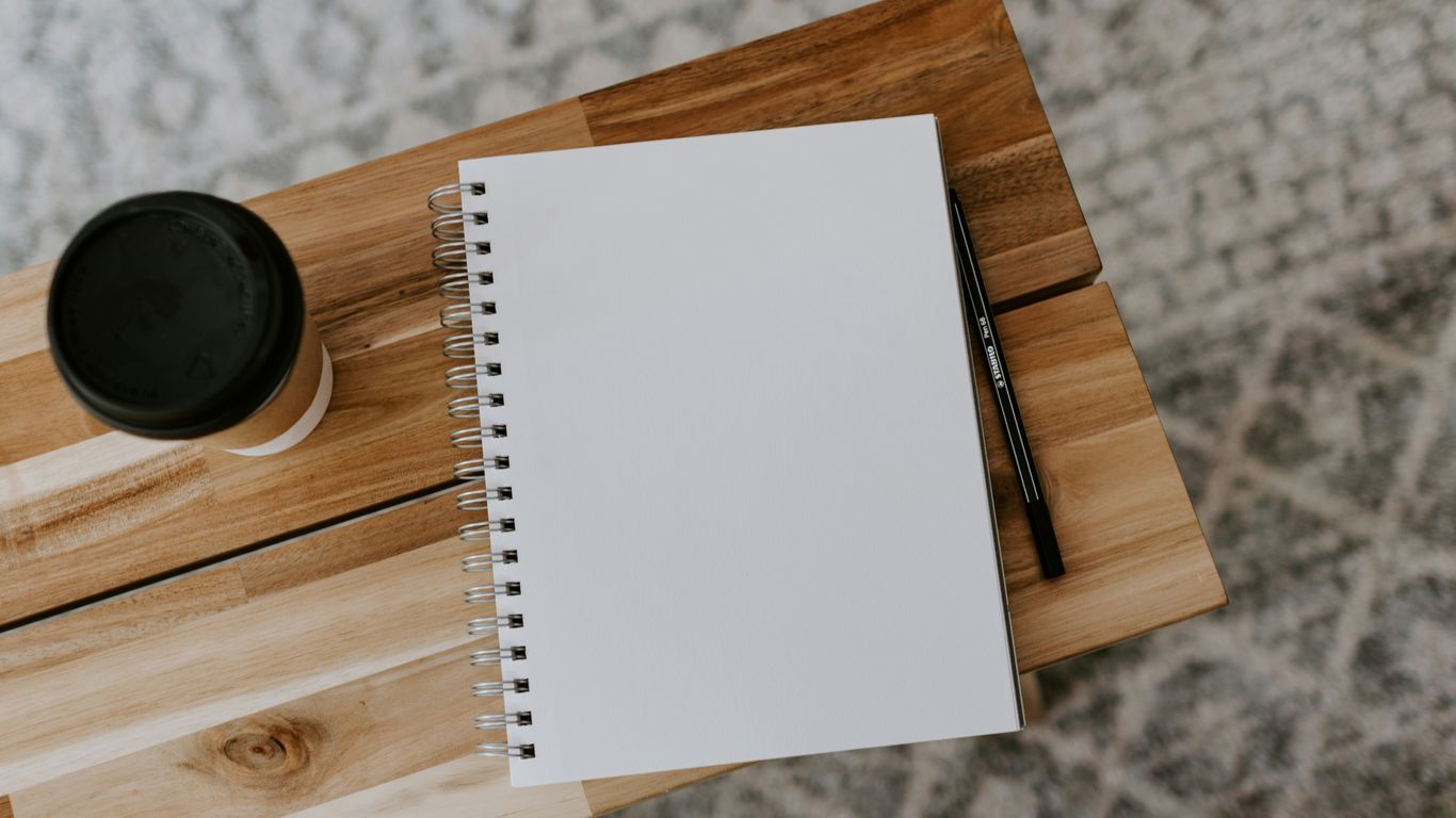 Notebook com café sobre uma mesa de trabalho