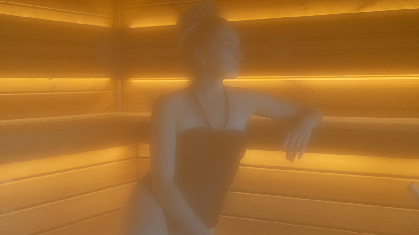 Woman relaxing in a steamy, wood-paneled sauna