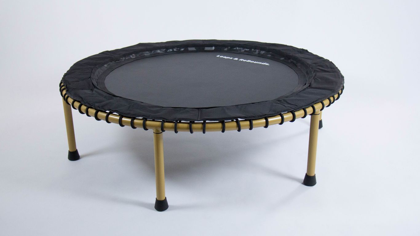 A small round trampoline with gold legs on white background.