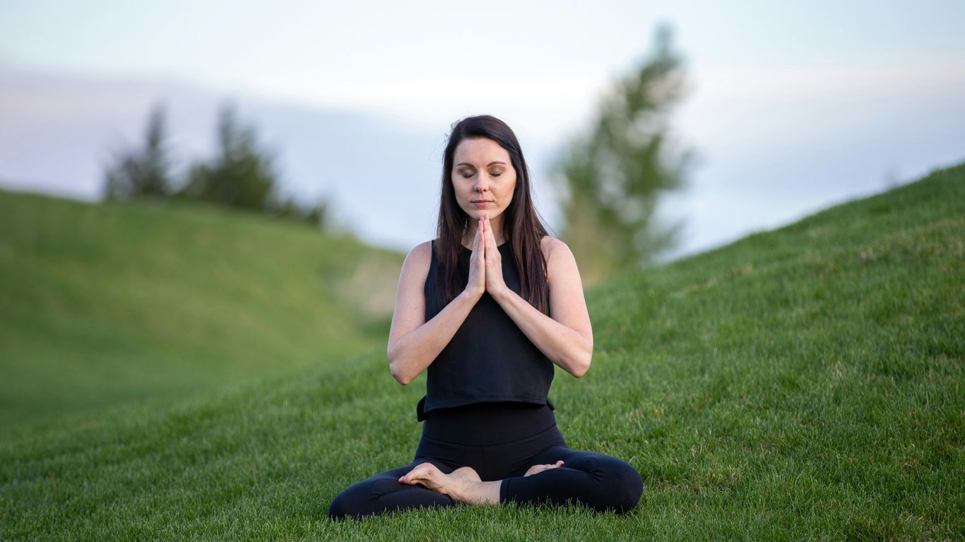 Person practicing yoga outdoors on a portable mat
