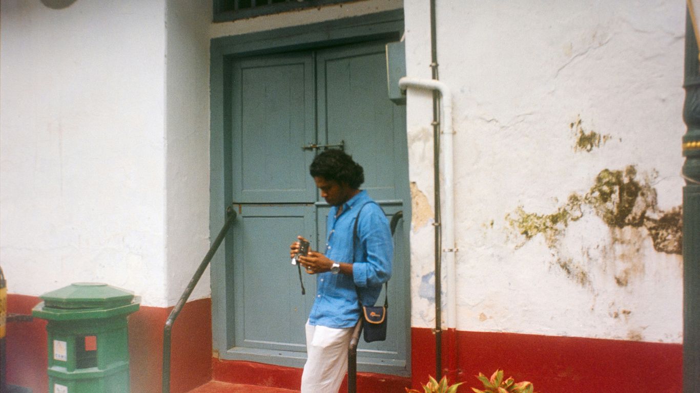 Man in blue shirt standing by a blue door.