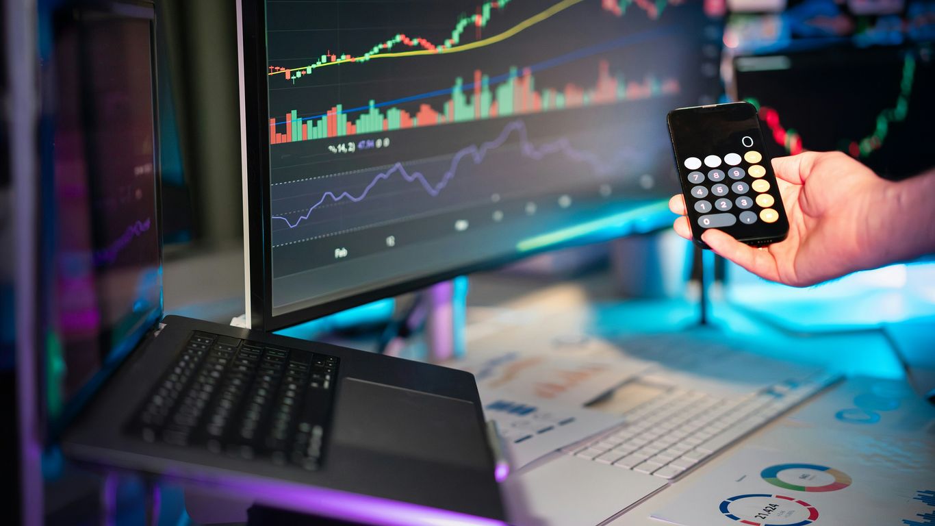 A person holding a remote control in front of a computer
