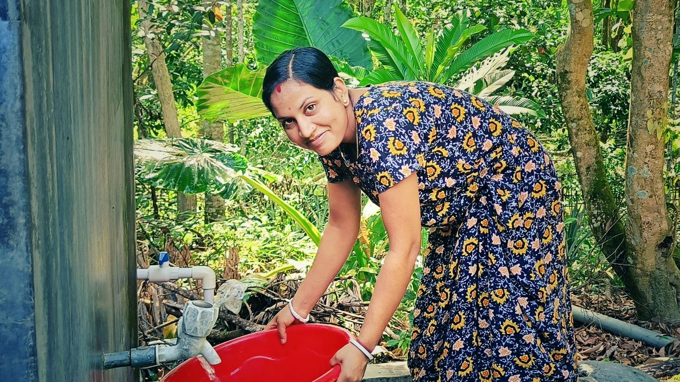 A woman is filling a red bucket with water