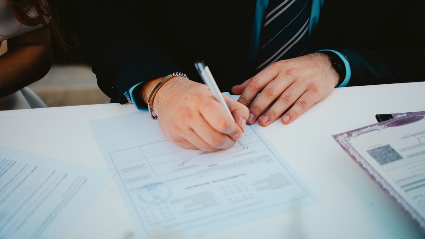 Person signing a document with a pen.