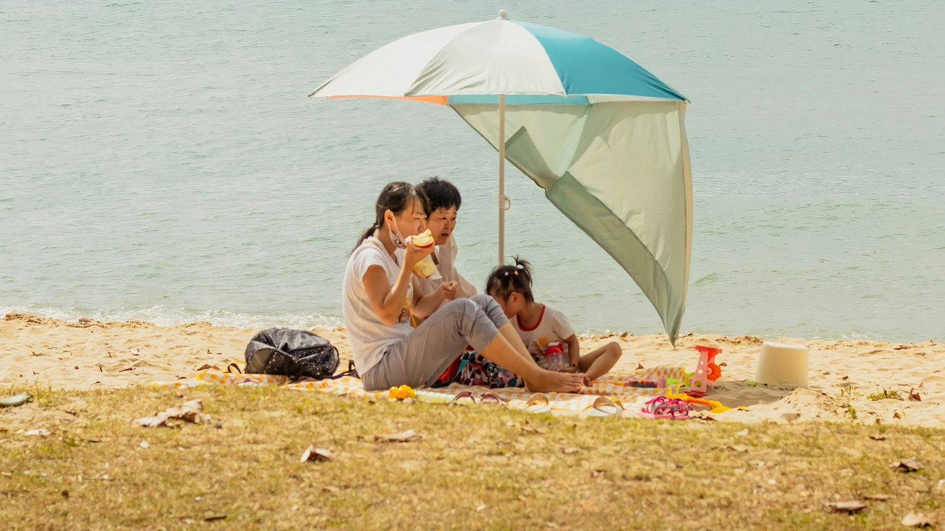 2 women sitting on beach sand during daytime