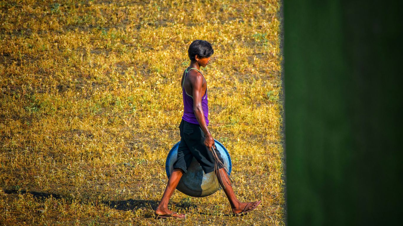 woman in purple tank top and blue denim shorts sitting on green grass field during daytime