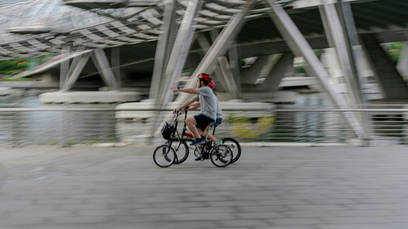 a man riding a bike down a street next to a bridge