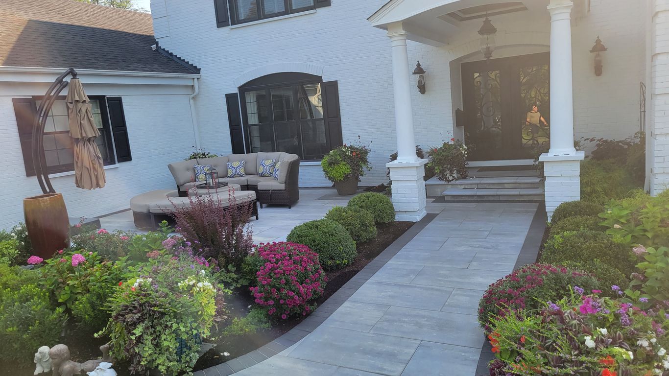 A white brick house with a beautiful garden and patio.