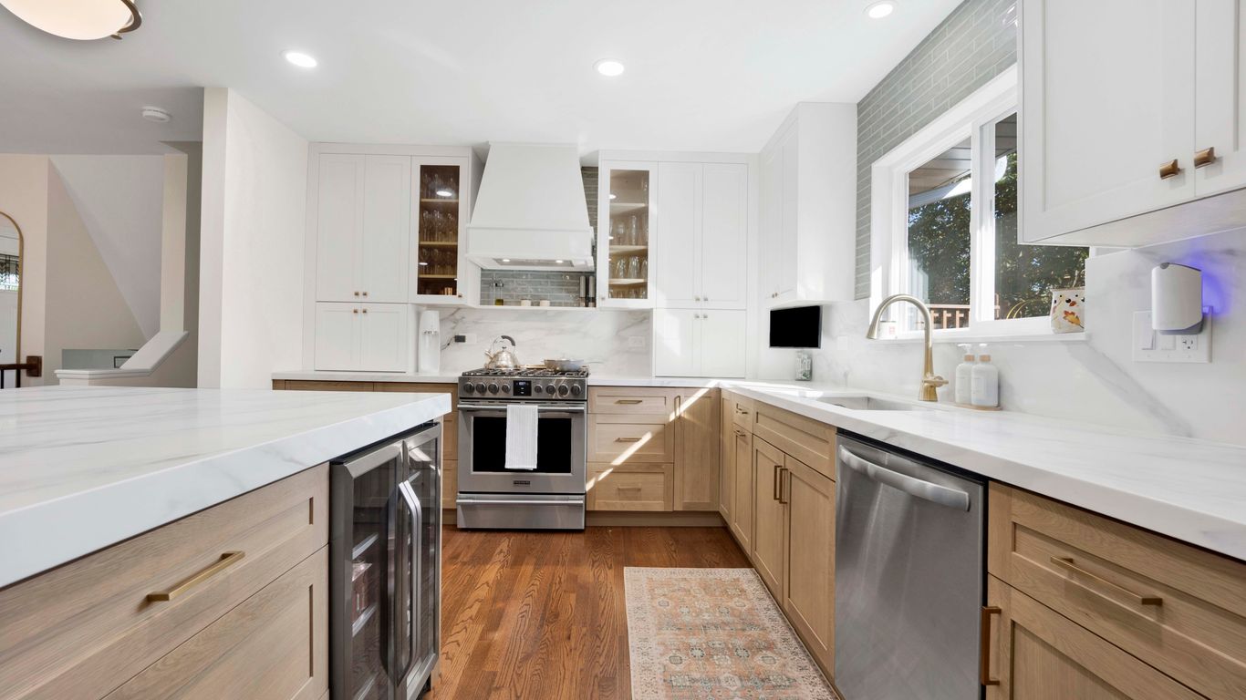 Modern kitchen with white cabinets, wood accents, and stainless steel appliances.
